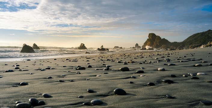 A sandy beach with pebbles in Westport, New Zealand