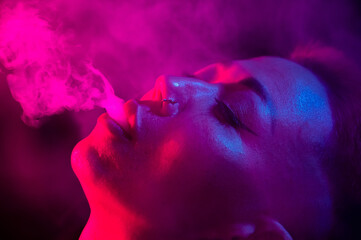 Asian woman with short haircut smoking in neon light. close-up portrait. 