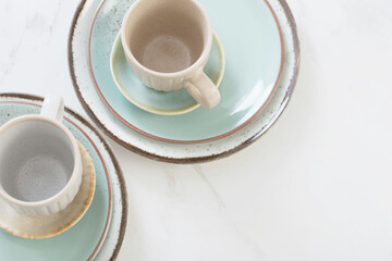 two ceramic cups and plates on white marble table