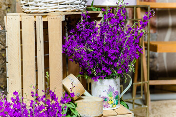 Close-up of lavender flowers in decorative watering can on floor decorated with wooden boxes