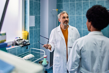 Obraz premium A serious male doctor holding his glasses and talking with an African female colleague.