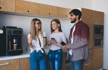 Cheerful coworkers drinking coffee in office kitchen
