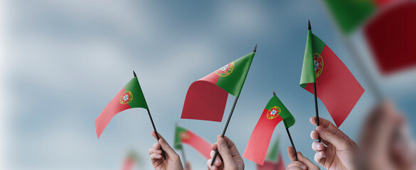 A group of people holding small flags of the Portugal in their hands