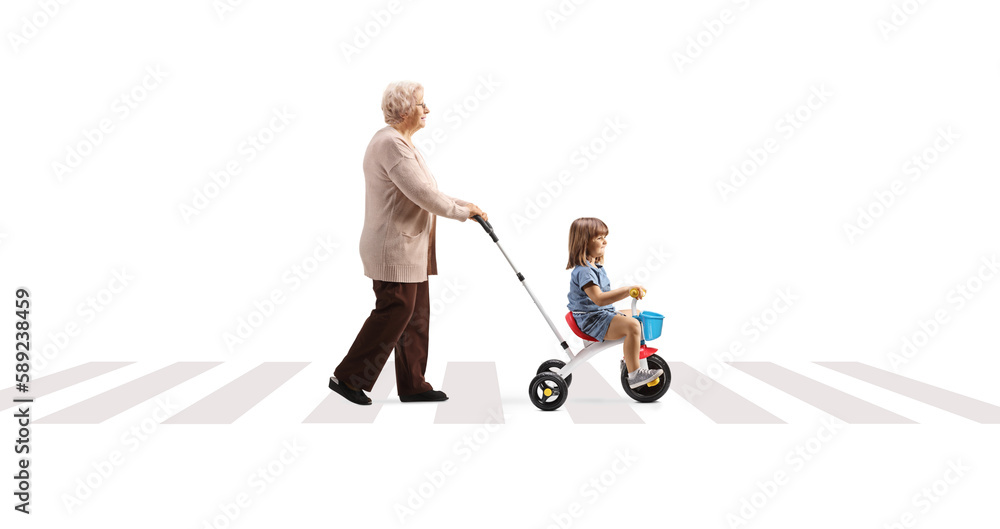 Canvas Prints full length profile shot of a grandmother pushing a child on a tricycle over pedestrian crossing