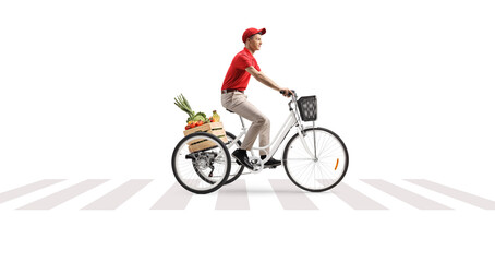 Delivery guy riding a tricycle with a crate of fruits and vegetables at a pedestrian crossing