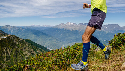 legs runner athlete in compression socks run down mountain, skyrunning race competition