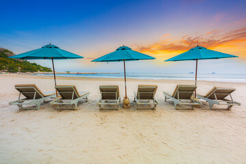 Beaches and sun tables in Thailand,Row of empty sun loungers and orange parasols on the tropical beach at sunset. Vacation in the all inclusive hotel on the Caribbean sea 
