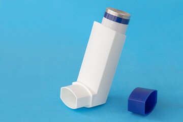 Asthma inhaler with blank label isolated on a blue background. Pharmaceutical product is used to...