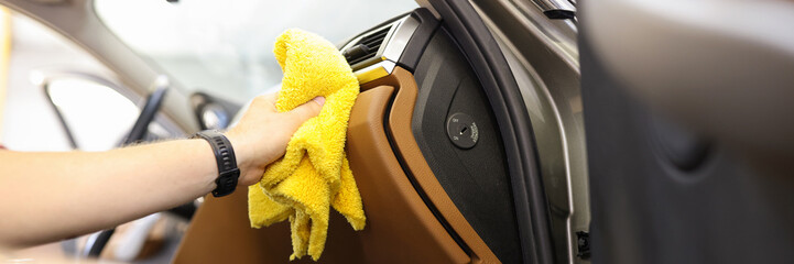 Close-up of male hand cleaning vehicle interior, cleaner washes car leather salon