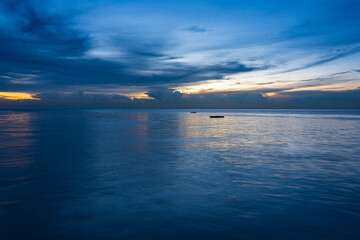 Wide angle shot of blue sea with calm waves and cloudy sky at twilight.