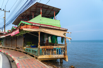 A decaying green cement house located in the sea where the wetlands are close to the road.