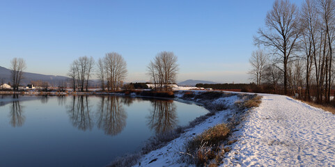 Obraz premium Snow and trees reflected in the water surface