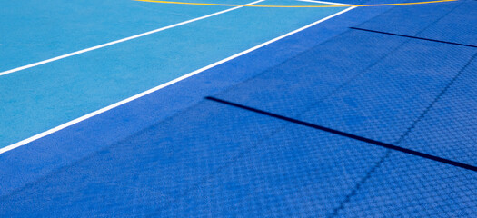 Fototapeta na wymiar Sport field court background. Blue rubberized and granulated ground surface with white, yellow lines and tennis net shadow on ground. Top view