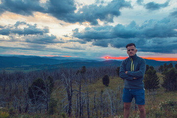 Travel, freedom and tourism concept - man standing on top of cliff in summer beauty evening in Altai mountains