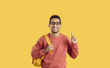 Ethnic male college or university student has a great idea. Happy young mixed race man who has found a solution to his problem is pointing his index finger up, smiling and looking at the camera