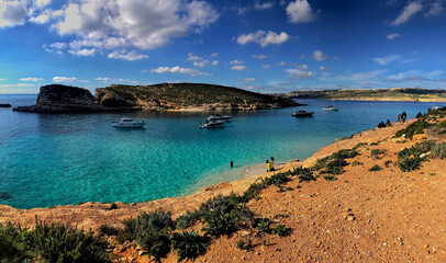 Obraz premium Beautiful beach with crystal blue waters, with people bathing. Boats and boats strolling through the waters of the island of comino in malta.