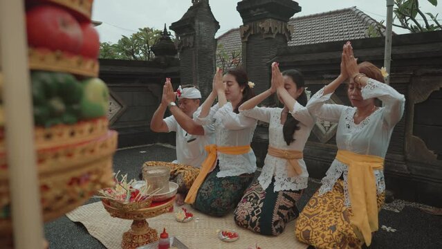 Balinese Family Performing Hindu Ritual Prayer Daily Offerings at Home Temple in Bali Indonesia Culture Religion