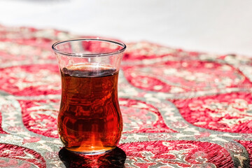 Cup of Turkish tea close up on tablecloth with turkish ornament