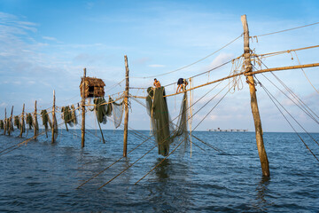 Silhouette of fishermen pulling a nets on fishing poles at sea in Tra Vinh province, Vietnam, Asia during sunrise, local people call it is Day hang khoi.