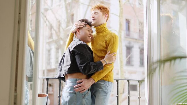 Gay couple embracing on the balcony at home