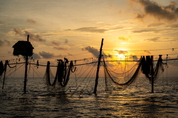 Silhouette of fishermen pulling a nets on fishing poles at sea in Tra Vinh province, Vietnam, Asia during sunrise, local people call it is Day hang khoi.