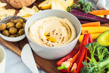 Hummus bowl with vegetables, fruits, olives, pita and crackers.