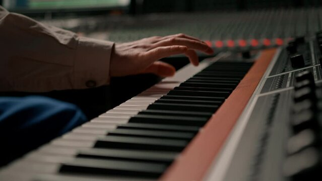 Male hands play electronic piano keyboard Fingers tap keys midi controller Musician produces song in recording studio