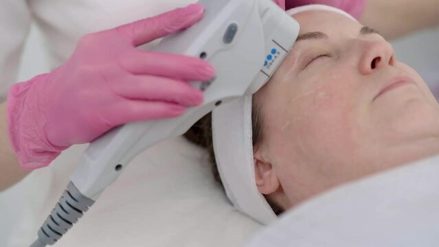 beauty center offers a peaceful setting for a female mature client to receive ultrasound face lifting massage with professional equipment. 