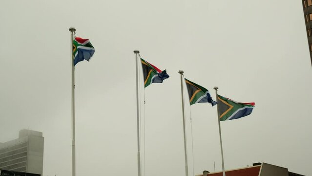 Four South African flags waving in the wind against a blue sky. South African flag against a foggy sky
