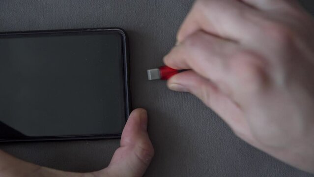 Man struggles to remove micro usb plug from cell phone socket
