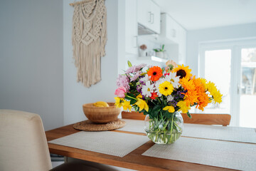 Kitchen counter table with focus on vase with huge multicolor various flower bouquet with blurred...