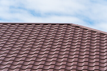 Red metal tile on the roof of the house. Modern types of roofing materials