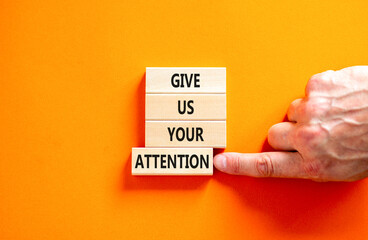 Give us your attention symbol. Concept words Give us your attention on wooden block. Beautiful orange table orange background. Motivational business give us your attention concept. Copy space.