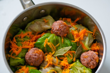 Raw vegan meatball with cabbage rolls and vegetables in cooking pan. Cooking process, homemade dinner. Vegan meat recipe