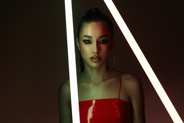 beautiful young woman with neon lamp. Pretty girl in latex