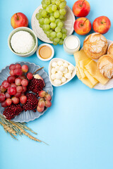 Jewish Shavuot Holiday Card. Dairy Products, Grapes, Cheese, Bread, Milk on Blue Background.