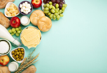 Jewish Shavuot Holiday Card. Dairy Products, Fruits, Cheese, Bread, Milk on Blue Mint Background.