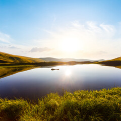 Fototapeta na wymiar small quiet mountain lake at the sunrise