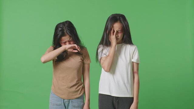 Young Asian Women Victims Of Violence With Bruise On Faces And Arms Crying On Green Screen Background In The Studio
