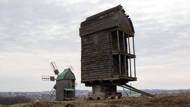 Old wooden windmills in the field. Ancient  windmills against the background of dark clouds.