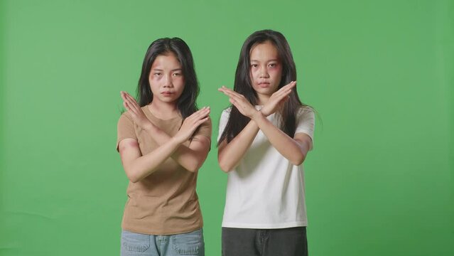 Young Asian Women Victims Of Violence With Bruise On Bodies Looks Into Camera Showing Hands Cross Gesture To Stop Violence In Green Screen Background Studio

