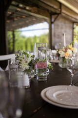 A very nicely decorated wedding table appointments with beautiful decor with plates and serviettes in spring garden. Beautiful flowers on table in wedding day. The elegant dinner table.