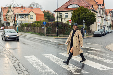 Young adult trendy stylish beautiful caucasian happy smiling woman enjoy walking by road crosswalk...
