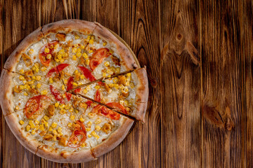 Pizza for children on a cream base with chicken fillet, tomatoes, corn and mozzarella cheese on wood background. Copy space.