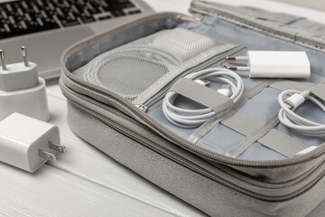 Puts wires of tablet advanced electronic equipment, phone charger in a convenient storage bag. Preparing for a business trip or vacation. Packing method for technological tools.