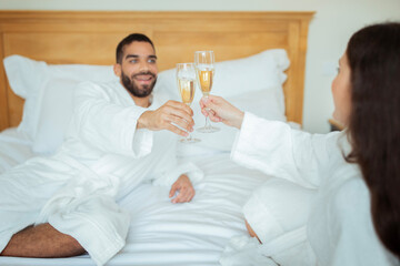 Couple Clinking Glasses Drinking Sparkling Wine Wearing Bathrobes In Hotel