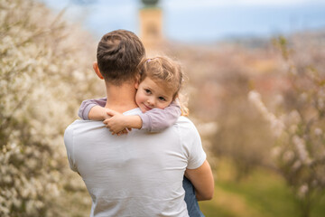 Father and daughter having a fun together under a blooming tree in spring park Petrin in Prague, Europe