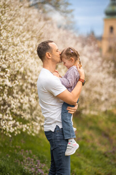 Father and daughter having a fun together under a blooming tree in spring park Petrin in Prague, Europe