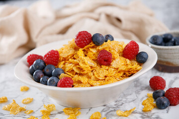 Close-up of corn flakes with blueberries and raspberries on a marble table