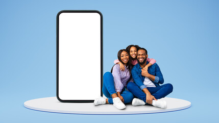 Smiling young african american woman and man sit on floor, small girl embracing parents